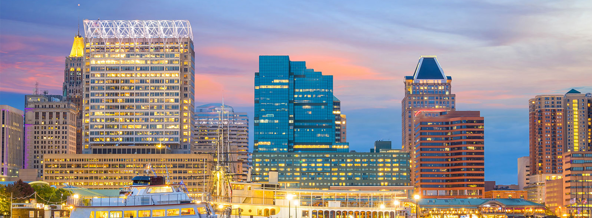 The image depicts a city skyline at sunset with illuminated buildings and a colorful sky, showcasing an urban landscape with a prominent skyscraper and a watermark indicating it s a stock photo.